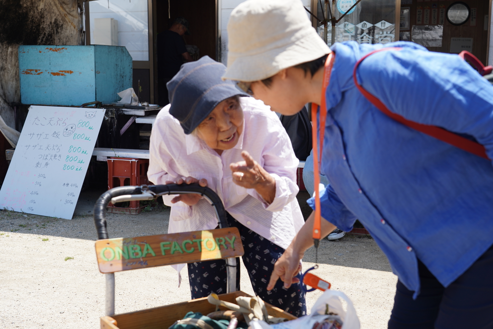 NSYSU Ph.D. student Yueh-O Wang (far right) engages in conversation with an elderly local woman pushing a cart.Image