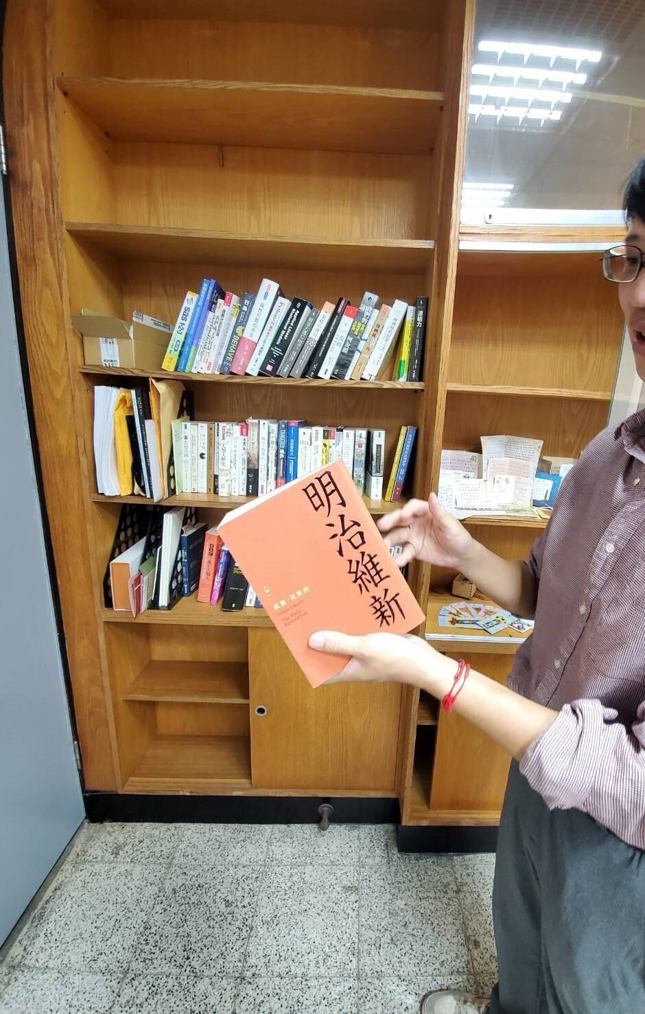 Professor Lo shows off the collection of books in his study room. There are also cards from students on his bookcaseImage