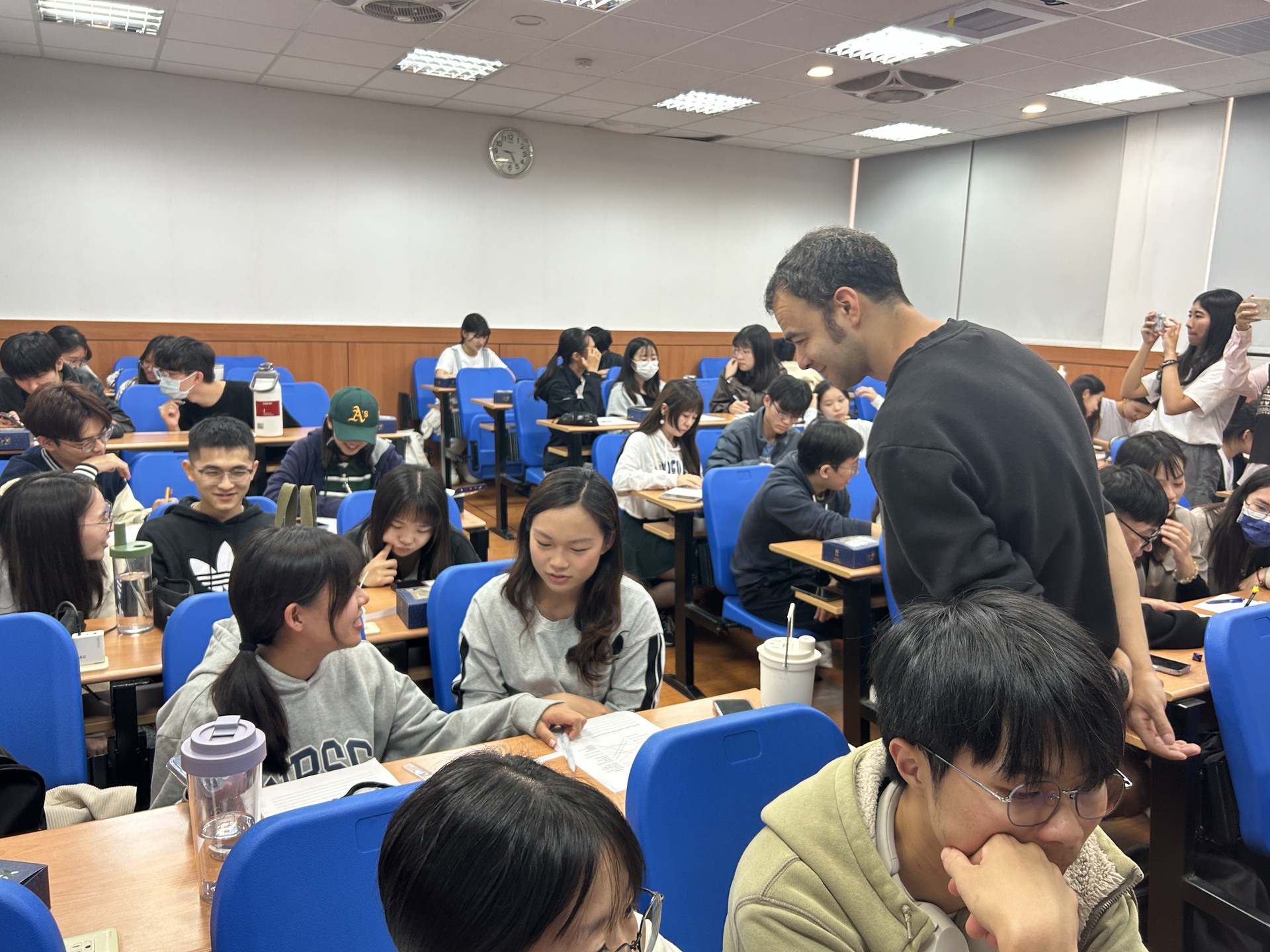 The speaker interacts with students during group discussions and offers guidance.Image