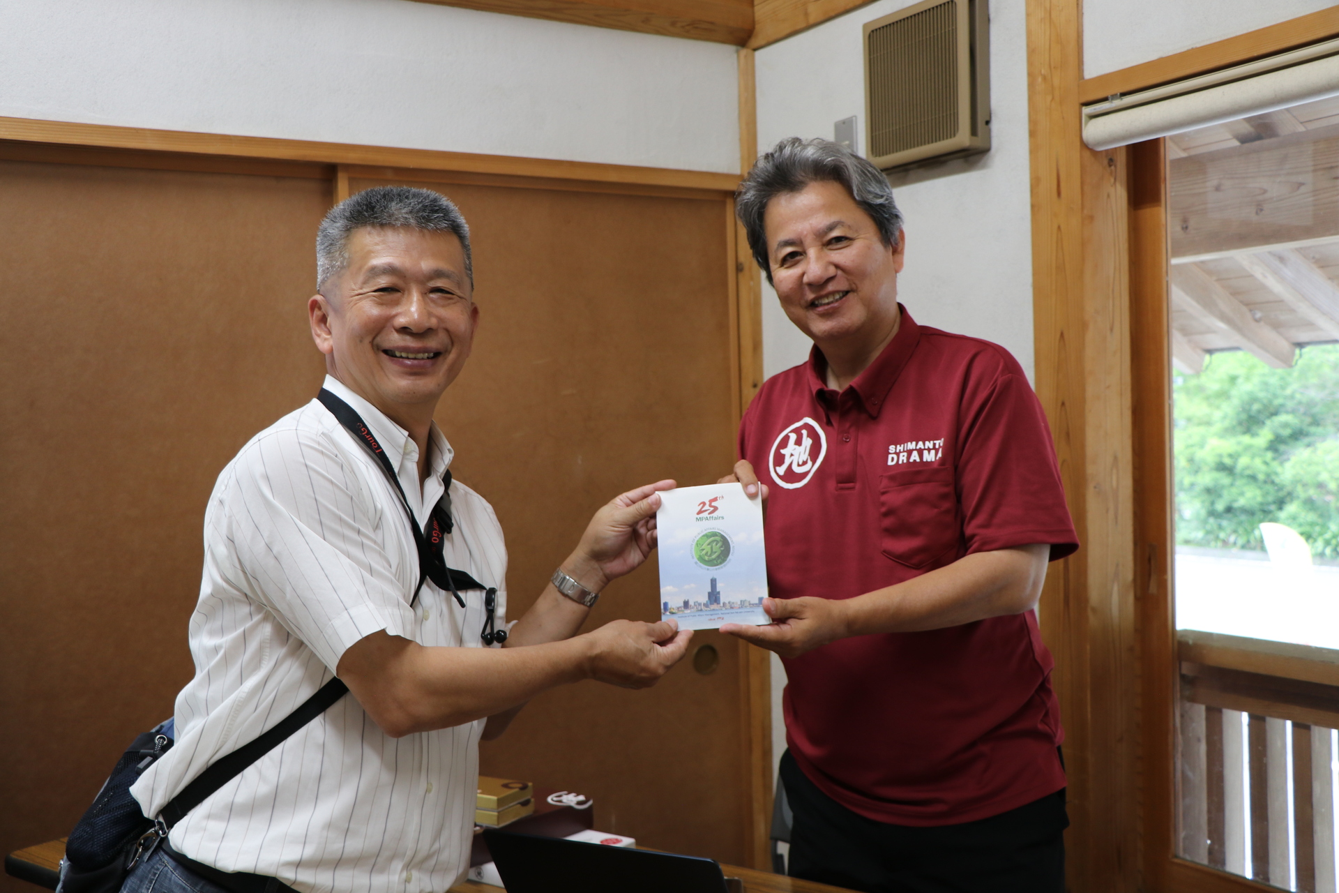 中山大學公事所郭瑞坤教授(圖左)致贈公事所一卡通予四萬十Drama會長畦地履正 (圖右)，並期盼未來到訪高雄，交流地方創生和永續教育議題。圖片
