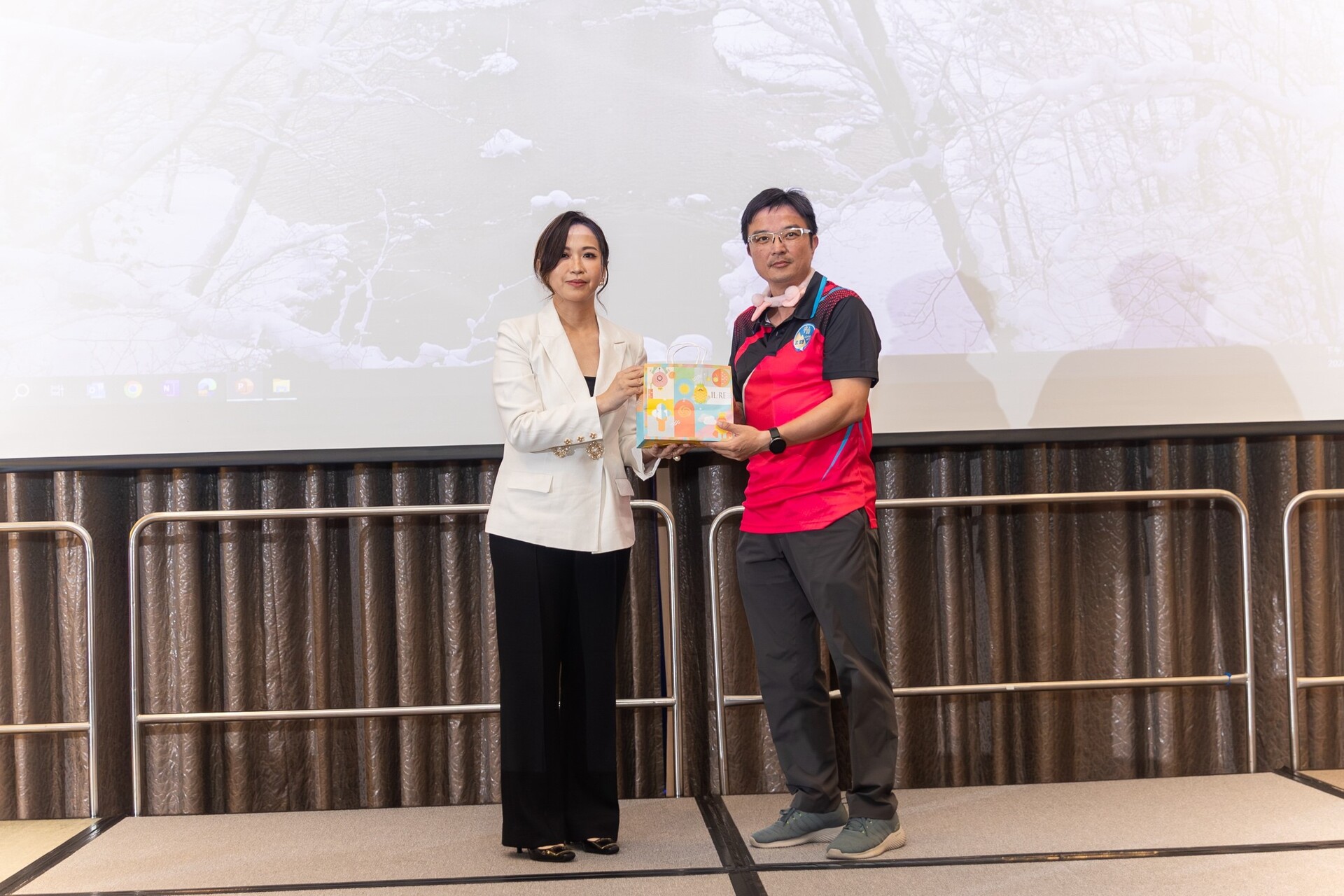第十屆理事長范瓊云(左)致贈禮品給北E9服務團隊共26人，由北E9總召葉乃維(右)代表領獎圖片