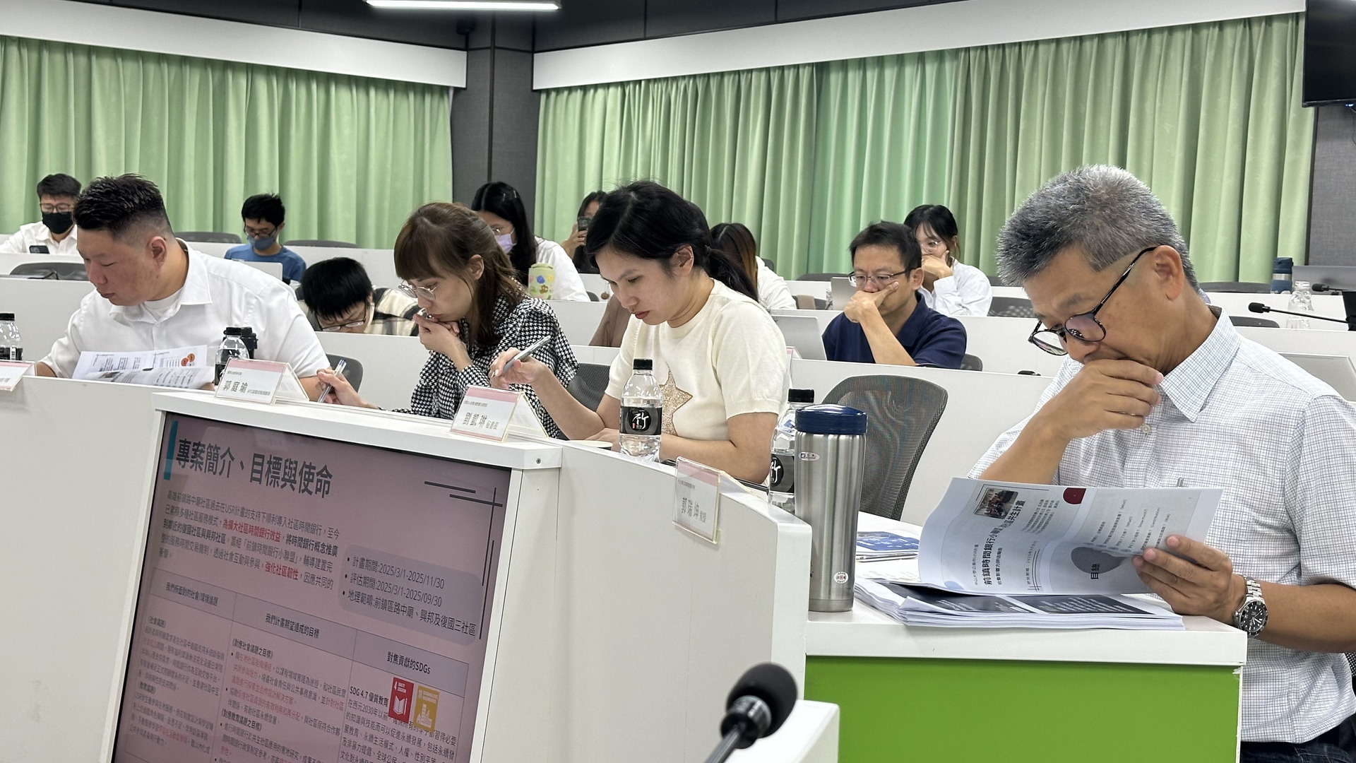 評審群聚精會神聆聽及審視專案影響力報告書圖片