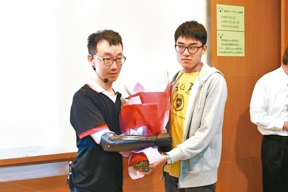 中山大學企管系助理教授王致遠（左）四肢截肢，去年3月裝上電子手臂及義肢後回校教書。 圖／取自中山大學管理學院圖片