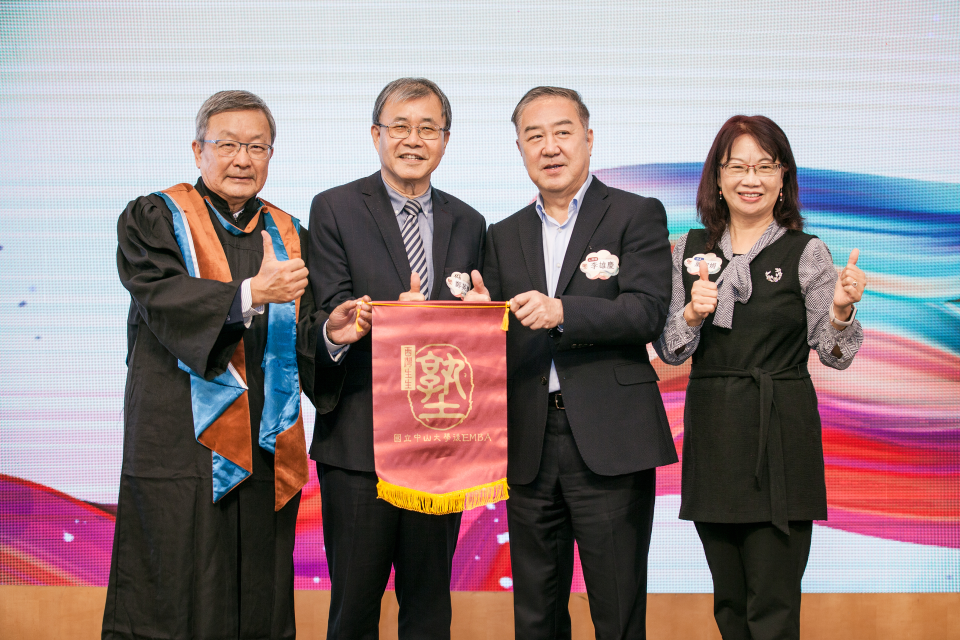 Dr. Chin-Nan Hsieh passed the Post-EMBA Flag to Dr. Hsung-Ching Li (second from right) during the inheritance ceremony. This represents that Post-EMBA, a practical wisdom learning hall, will continue to grow.Image